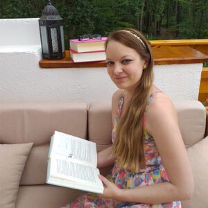 Monika Schulze sitzt auf einem Balkon mit einem Buch in der Hand