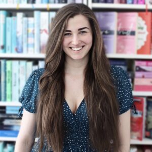 Ramona vor einer bunten Bücherwand. Sie ist Jurymitglied beim tolino media Newcomerpreis 2022