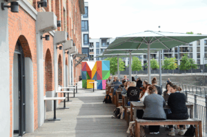 Terrasse am Wasser mit mehreren Menschen auf Bänken